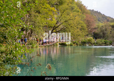 Besucher genießen den Spaziergang entlang der Holz- weg an der Seite von einem der Plitvicer Seen in Kroatien. Stockfoto