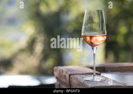 Horizontal im Freien geschossen bei Sonnenuntergang, ein elegantes Glas Wein rosè. Gegenstand und auf die richtigen Schwerpunkte Stockfoto