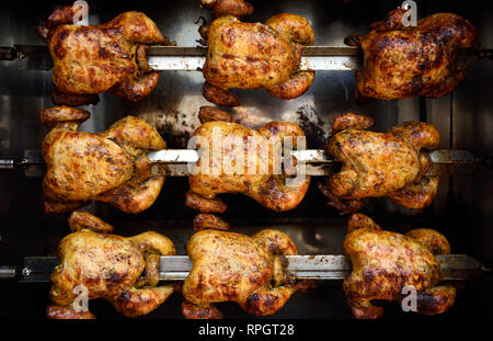 Reihen von heiss gebraten Spieß gekocht ganze Hühner, oder Grillhähnchen in Kolumbien, Südamerika. Stockfoto