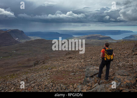 Wanderer in Richtung Arnarfjordur Fjord aus dem Berg von Lomfell. Westfjorde, Island. Stockfoto