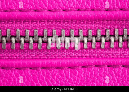 Metall Reißverschluss auf intensive rosa lila Leder Jacke oder Handtasche Detail Nahaufnahme Makro. Der Reißverschluss ist fest verschlossen verbindlich zusammen Die beiden textilen Schicht Stockfoto
