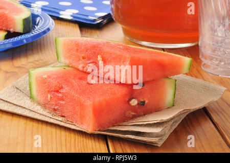 Frische Wassermelone auf einem Holztisch mit Kanne Eistee Stockfoto