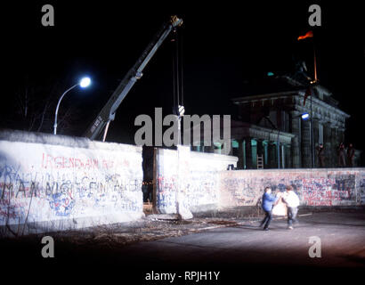 Die Anwohner freuen sich als Kran einen Abschnitt der Berliner Mauer neben dem Brandenburger Tor entfernt. Stockfoto