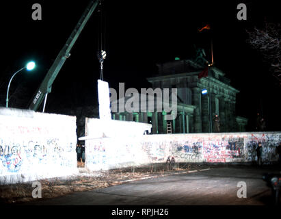 Ostdeutsche wachen Fotos als Kran einen Abschnitt der Berliner Mauer neben dem Brandenburger Tor entfernt. Stockfoto