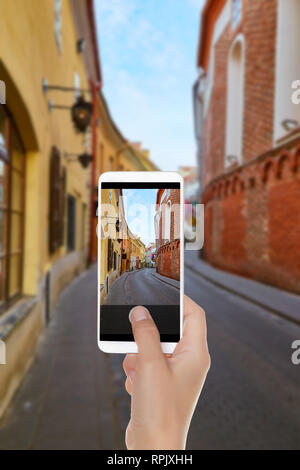 Ein Mann macht ein Foto von leere Straße in der Altstadt der Hauptstadt von Litauen - Vilnius auf einem Mobiltelefon Stockfoto