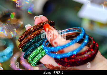 Eine Frau tragen Mehndi Design auf ihre Hand, bunten/bunte Glas Armbänder/Armreifen zum Verkauf an laad Basar, Hyderabad, Telangana, Indien. Stockfoto