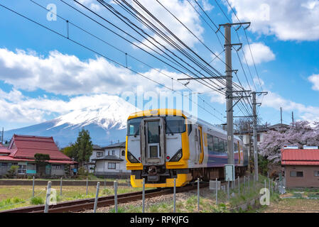 Fujikyu Bahn railroad Track mit Schnee bedeckten Berg Fuji (Mt. Fuji) Hintergrund in Kirschblüten Frühling. Fujiyoshida, Yamanashi, Japan Stockfoto