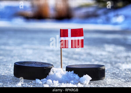 Ein Dänemark Flagge auf zahnstocher zwischen zwei Hockey Pucks. Ein Dänemark wird das Spielen auf Wm in Gruppe A 2019 Eishockey Weltmeisterschaft in Bratislav Stockfoto