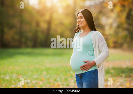 Gerne schwangere Frau im Park. Stockfoto