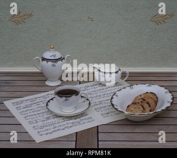 Englisch Teetasse mit Untertasse, creme Kanne, Sugar Bowl und einem Kuchen Schüssel mit Cookies, Fine Bone China Porzellan, auf einem Blatt von Musik Stockfoto