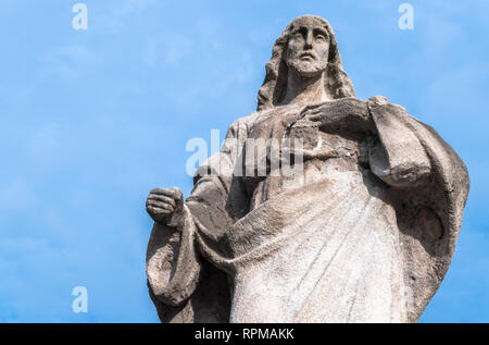 Steinerne Statue des Heiligen Herzens Jesu. Jesus Christus Stein Skulptur mit Herz auf und blauer Himmel. Ideal für Ostern Konzept und andere. Stockfoto