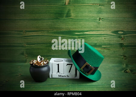 Weißer block Kalender für St Patrick's Day, 17. März, mit Kobold hat und Pot of Gold, am grünen Holz- Hintergrund. Stockfoto