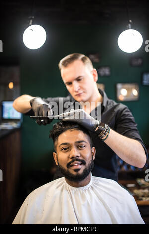 Junger bärtiger Mann, Haarschnitt, Friseur, während im Stuhl sitzen im barbershop Stockfoto