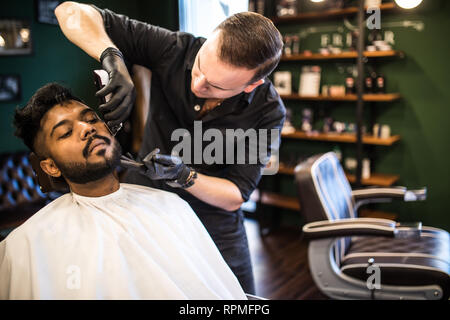 Close up Mann mit Bart Client im barbershop Friseur Friseur auf elektrische Rasierer rasieren. Stockfoto
