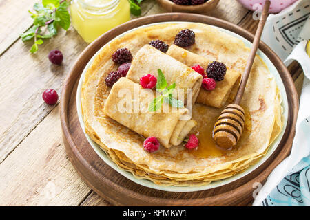 Gesunde Pfannkuchen Frühstück. Stapel von hausgemachten dünne Pfannkuchen oder Crepes auf einer rustikalen Tisch, mit Honig und frischen Beeren serviert. Kopieren Sie Platz. Stockfoto