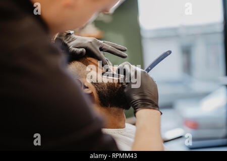 Geschickte Friseur. Junger Mann altmodisch Rasur mit einem Rasiermesser alt - Stockfoto