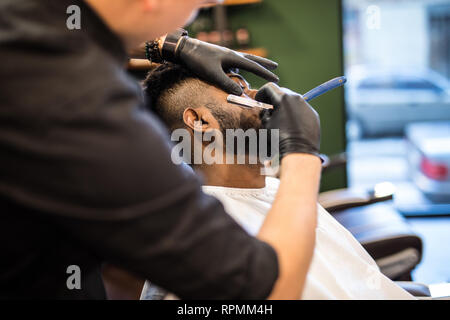 Geschickte Friseur. Junger Mann altmodisch Rasur mit einem Rasiermesser alt - Stockfoto