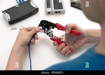 Techniker mit Netzwerkkabel crimper. Werkzeug zum Crimpen von Twisted Pair Kabel und Steckverbinder. Stockfoto