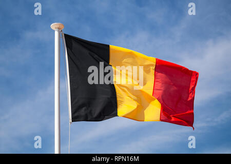 Flagge Belgiens winken auf Wind über blauen bewölkten Himmel Hintergrund Stockfoto