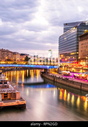 Riverboats und Cafés entlang des Donaukanals (Donaukanal) bei Sonnenuntergang, in der Nähe Schwedenplatz, Wien, Österreich Stockfoto