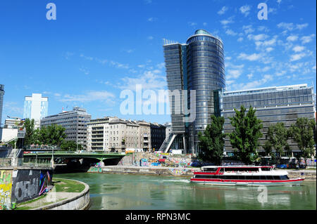 Bootstour entlang des Donaukanals (Donaukanal), in der Innenstadt von Wien, Österreich. Auf der anderen Seite des Flusses, die moderne Architektur der Uniqa Tower. Stockfoto