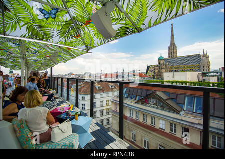 Menschen mit einem Getränk und genießen die Aussicht über Stephansdom von der Bar auf der Dachterrasse der Lamée Hotel in Wien, Österreich Stockfoto