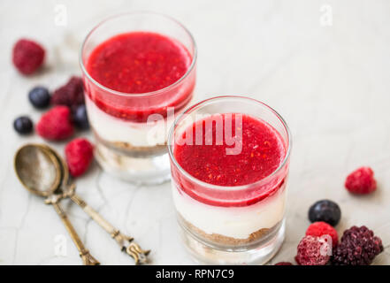 Glas Desserts mit Schichten von Keksen, Frischkäse Mascarpone und Beeren jelly Topping, geschichtetes Glas Desserts mit Himbeeren und Blaubeeren und Stockfoto