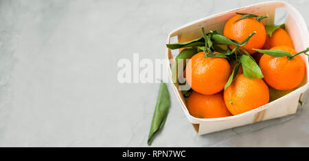 Frische Clementinen Zitrusfrüchte in einem Korb mit Kopie Raum, gesunde organische Clementinen mit Blättern Ansicht von oben in einen Korb auf konkreten Hintergrund kopieren Stockfoto