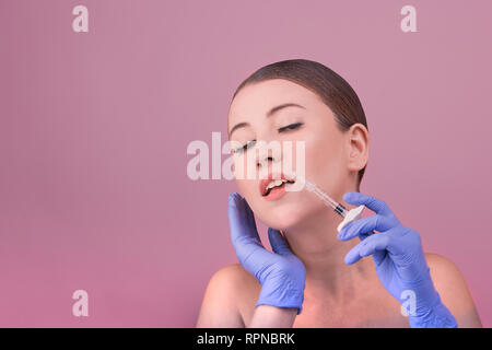 Frauen mit perfekter Haut posing hält eine Spritze in der Hand. Konzeptionelle Bild der plastischen Chirurgie Opfer Stockfoto