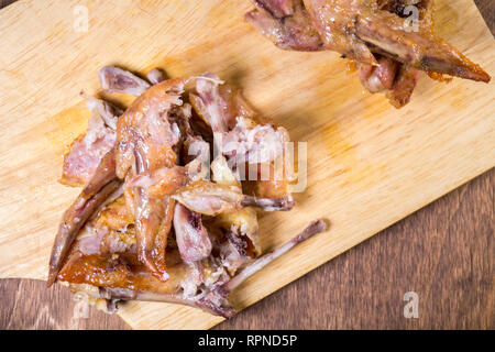 Reste von Huhn, Knochen liegen auf Flügeln auf Holzbrett Stockfoto