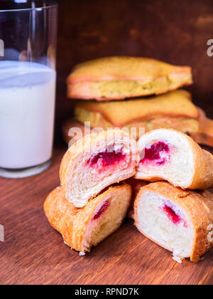 Frisches croissant Kirsche in ein Schnitt liegt auf der jeweils anderen, neben den Kuchen und Milch Stockfoto