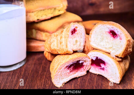 Frisches croissant Kirsche in ein Schnitt liegt auf der jeweils anderen, neben den Kuchen und Milch Stockfoto