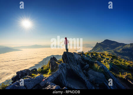 Reisenden, die auf dem Felsen, Doi pha Tang und morgen Nebel in Chiang Rai, Thailand. Stockfoto