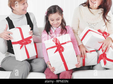 Großmutter, Mutter und Tochter mit geschenkboxen Sitzen auf der Couch. Urlaub Konzept Stockfoto