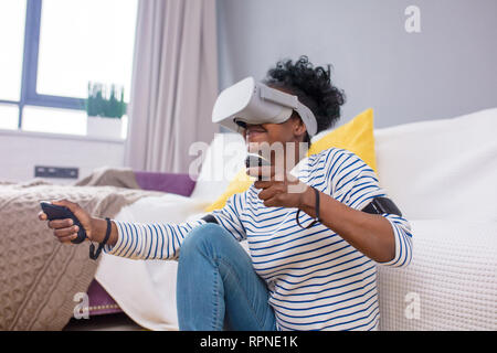 Cool tausendjährigen afrikanischen amerikanischen Frau Raum erkunden Sie mit Virtual reality Brillen, die Wahl der Innenraum für Ihre neue Wohnung Stockfoto