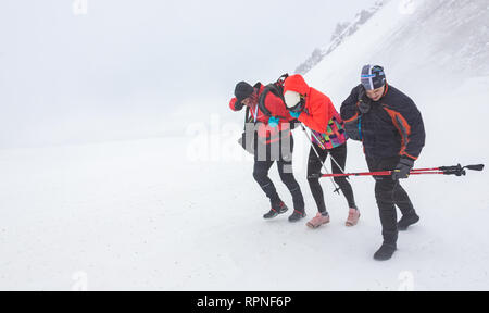 ALMATY, Kasachstan - 03 Februar 2019: Nicht identifizierte Personen durch einen Schneesturm zu Fuß während des AlpineRais Wettbewerb in den Bergen während der Stockfoto