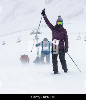 ALMATY, Kasachstan - 03 Februar 2019: Nicht identifizierte Personen durch einen Schneesturm zu Fuß während des AlpineRais Wettbewerb in den Bergen während der Stockfoto