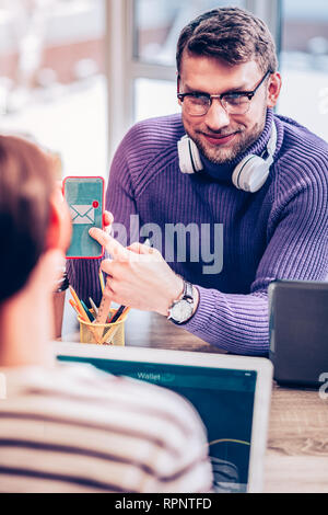 Rätselhafte brunette männliche Person an Mitarbeiter suchen Stockfoto