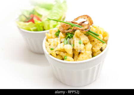 Käse Spätzle mit gerösteten Zwiebeln und Petersilie in einer weißen Schüssel auf weiße Platte Stockfoto