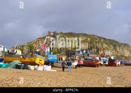 Paar bummeln Vergangenheit Hastings Fischerboote auf die Altstadt Stade Strand an einem stürmischen Tag im Winter, East Sussex, Großbritannien Stockfoto