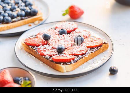 Close-up Frühstück sweet Toast mit Nutella, Erdbeere, Heidelbeere und Kokos Chips. Stockfoto