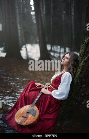 Mädchen in ein altes Kleid mit einer Gitarre im Wald Stockfoto