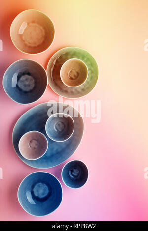 Schöne blau, grau, beige Geschirr, Teller Schalen auf rosa Hintergrund Tabelle, Ansicht von oben, lebendige Farben, Neonfarben, selektiven Fokus Stockfoto