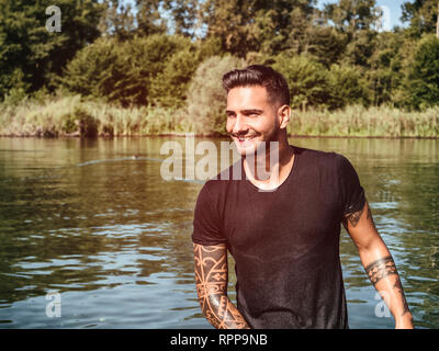 Schöner Mann im Teich mit Wet t-shirt Stockfoto