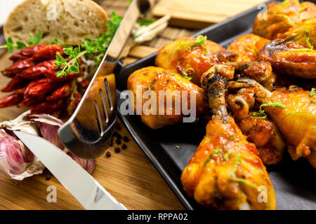 Gebratene Hühnerkeule mit Ingwer, Chili und Zwiebeln auf einem Holzbrett serviert. Stockfoto