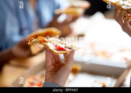 Nahaufnahme der weiblichen Hand Stück Pizza, Freunde zusammen in Cafe Stockfoto