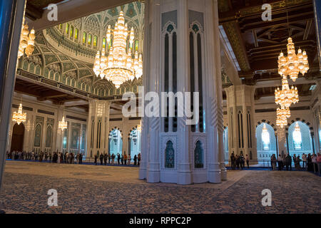 Muscat, Oman - November 4, 2018: Beleuchtete Kronleuchter in der Großen Moschee von Muscat mit Gläubigen und turiusti (Oman) Stockfoto