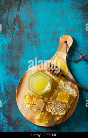 Natürlicher Honig. Honig im Glas und Pendelarm, Süße Waben auf blauen Tisch aus Stein. Ansicht von oben flach Hintergrund. Kopieren Sie Platz. Stockfoto