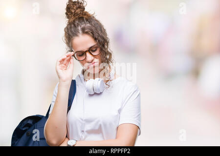 Junge brünette Studentin Mädchen mit Rucksack und Kopfhörer über isolierte Hintergrund denken müde und mit Depressionen Probleme mit Cr gelangweilt Stockfoto