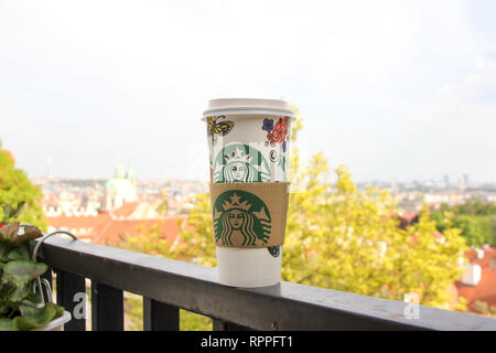 Helle Stadt Ansicht mit Starbucks Papier Tasse Kaffee steht auf dem Balkon Geländer im Vordergrund. Schönen goldenen Herbst Baum Stockfoto